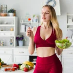 Mulher praticando hábitos saudáveis comendo verduras e legumes na cozinha